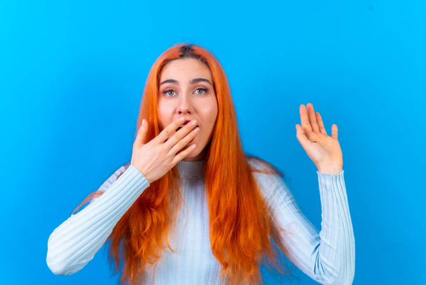 Red-haired woman in studio photography making the astonished gesture on a blue background - Photo, Image