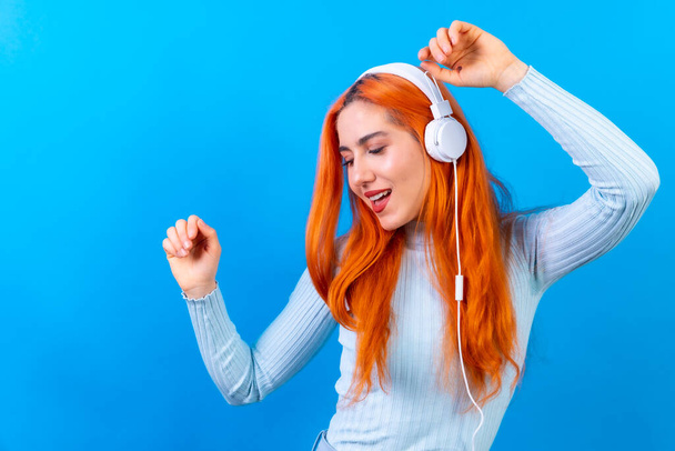 Redhead woman in studio photography smiling dancing on a blue background - Фото, зображення