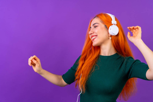 Redhead woman in studio photography dancing on a purple background - Foto, Imagem