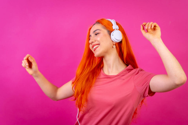 Redhead woman in studio photography dancing smiling on a pink background - Φωτογραφία, εικόνα