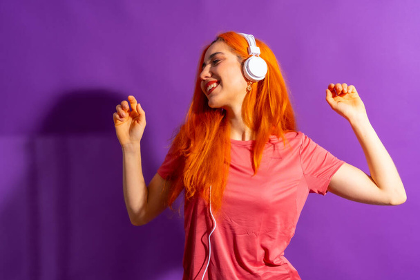 Redhead woman in studio photography dancing on a purple background, with a hard light - Foto, Imagem