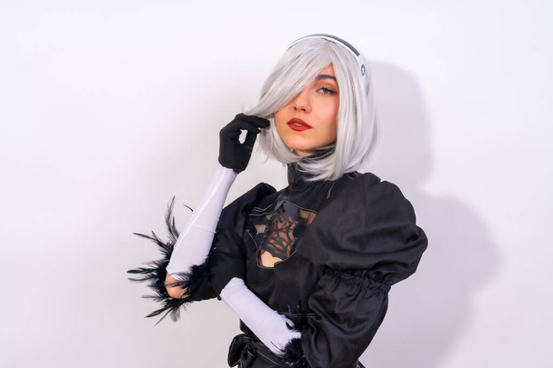 Portrait of cosplay woman in a black costume and a white wig in studio on a white background - 写真・画像