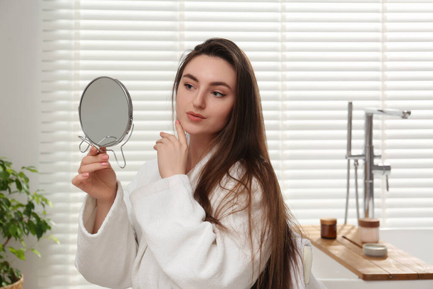Beautiful woman looking in mirror in bathroom - Foto, imagen