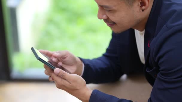 Geschäftsinhaber oder asiatische männliche Vermarkter nutzen Smartphones bei der Büroarbeit. Hochwertiges 4k Filmmaterial - Filmmaterial, Video