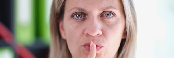 Close-up of serious female showing shh sign with finger or to keep silent gesture. Woman holding finger near lips. Quiet place and silence time concept - Фото, зображення