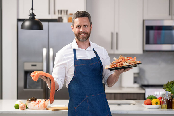positive chef cooking lobster and salmon seafood. chef with lobster and salmon seafood in the kitchen. photo of chef with lobster and salmon seafood. chef with lobster and salmon seafood. - Фото, зображення