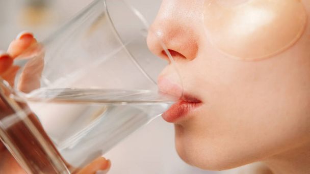 Hydration diet. Skin detox. Beauty routine. Closeup profile of unrecognizable thirsty woman with clean face hydrogel under eye patches enjoying drinking mineral water. - Photo, image