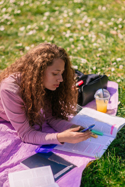 Κορίτσι που χρησιμοποιεί αριθμομηχανή ενώ σπουδάζει στο πάρκο - Φωτογραφία, εικόνα