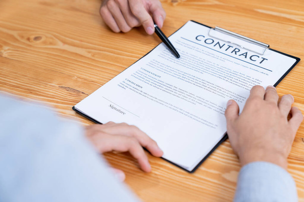 Businessman carefully reviewing contract document for corporate partnership. Client reading agreement deal and terms on meeting table for professional business decision. Entity - Foto, Imagem