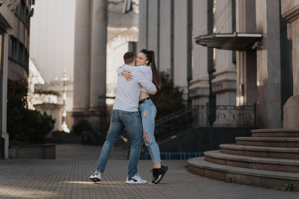 Beautiful couple hugging while standing between the buildings at the city - Foto, imagen