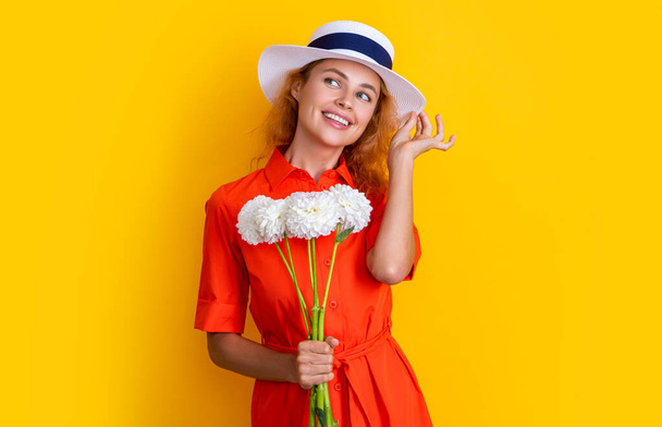 dreamy girl with mothers day flowers in studio. girl with mothers day flowers on background. photo of girl with mothers day chrysanthemum flowers. girl with mothers day flowers isolated on yellow. - Foto, afbeelding
