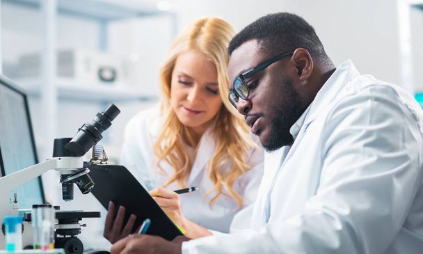 Medical scientists working in lab. Doctor teaching interns to make analyzing research. Laboratory tools: microscope, test tubes, equipment. The concept of biotechnology, bacteriology, virology and health care. - Photo, image