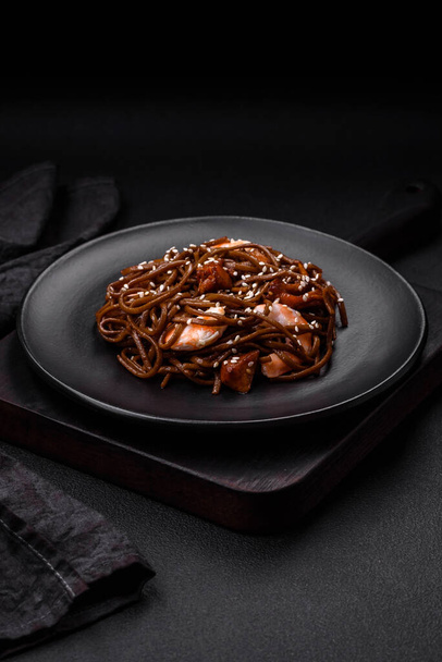 Delicious fresh buckwheat noodles with boiled tiger prawns, salt, spices and mushrooms on a dark concrete background - Foto, Bild