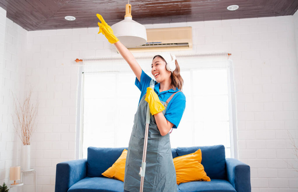 Happy Housework or house keeping service female singing and cleaning dust in house, cleaning agency small business. professional equipment cleaning old home. - Foto, Bild