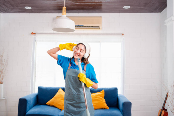 Happy Housework ya da ev hizmetçisi kadın şarkı söyleyip tozları temizliyor, küçük işletmeleri temizliyor. profesyonel ekipman eski evi temizliyor. - Fotoğraf, Görsel