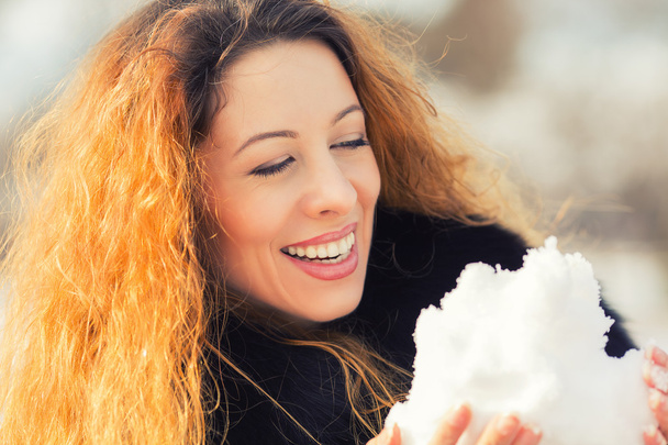 Carefree woman with long curly hair playing with snow in park - Photo, Image