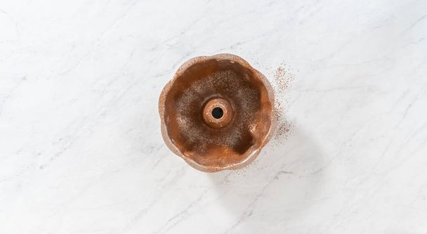 Flat lay. Greasing metal bundt cake pan with vegetable shortening and cocoa powder to bake gingerbread bundt cake with caramel filling. - Photo, image