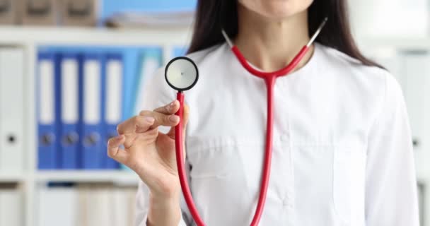 Female doctor holding red stethoscope in clinic closeup 4k movie slow motion. Professional medical advice concept - Séquence, vidéo