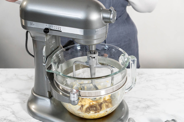 Mengen van ingrediënten in een keuken stand mixer om zachte havermout rozijnen walnoot koekjes bakken. - Foto, afbeelding