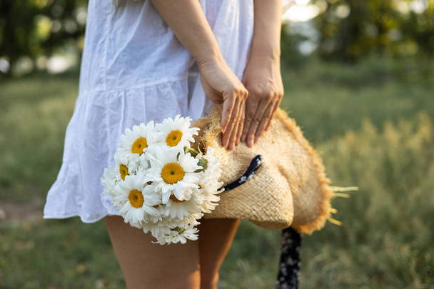 girl in white dress plucks daisies on the field - Foto, immagini