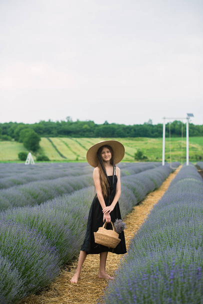 Beautiful girl with long hair in a lavender field. Beautiful girl in a hat. Summer in the lavender field - Foto, Imagen