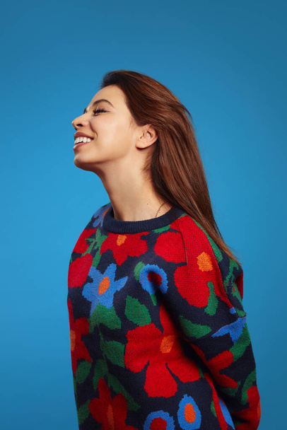 Vertical photo of side view lovely positive latin girl with closed eyes and charming smile, being in high spirit, isolated over blue background - Fotografie, Obrázek
