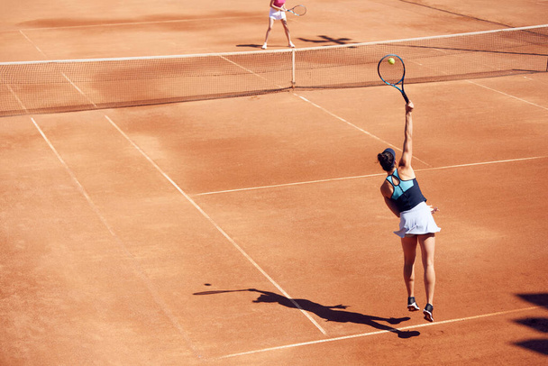 Top view image of professional tennis player in motion, young woman during game, training at open air stadium, court. Concept of sport, hobby, active lifestyle, health, endurance and strength, ad - Фото, изображение