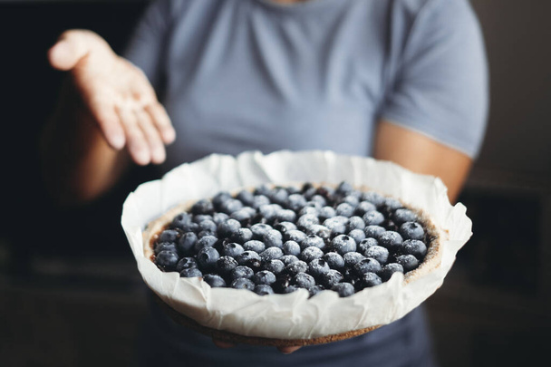 Close up of healthy and natural handmade blueberries cake. Homemade bakery concept food. Unrecognizable woman in background. Natural healthy lifestyle nutrition, dieting cakes. Berries fruit. - Foto, imagen