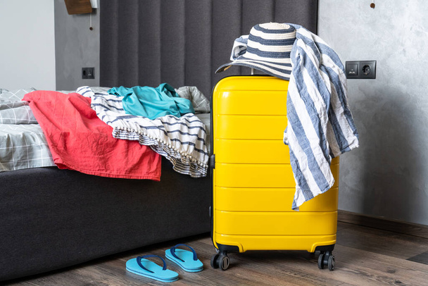 Gepäckpacken für Sommerreisen im Schlafzimmer. Koffer mit Sommertuch und Hut. - Foto, Bild