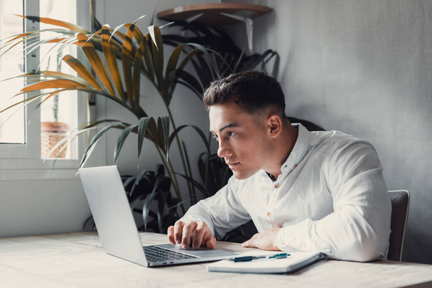 komea nuori liikemies kannettava tietokone pöydällä, mies katselee näytön keskittyminen  - Valokuva, kuva