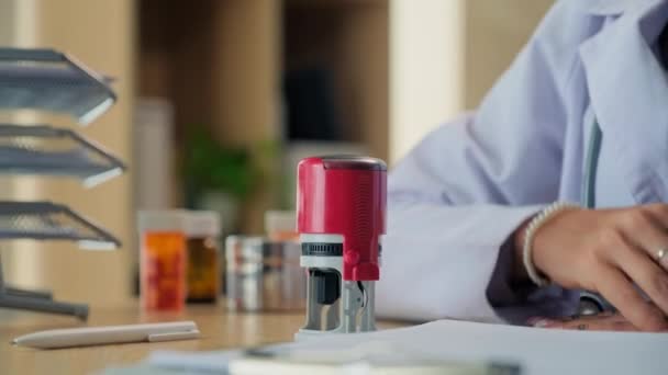 lähikuva naisen käsi labcoat leimaamalla lääketieteellinen asiakirja toimistossa - Materiaali, video