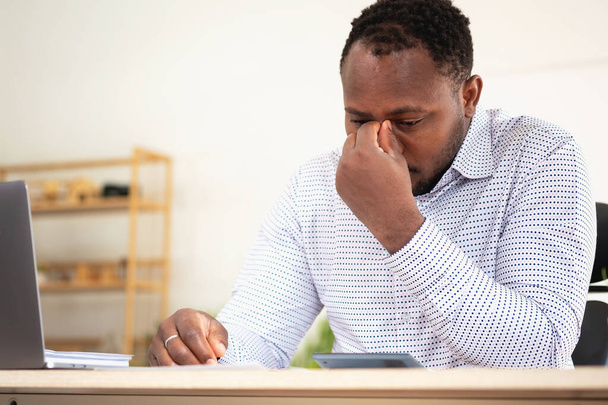 An American businessman with black skin in Africa feels uncomfortable at work and wrist pain is caused by the accumulated stress from failing to complete the job. and the body rests a little.  - Photo, image