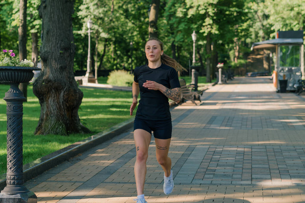 Fitness young sportswoman girl doing sports in the morning running during training outdoors in the city in park healthy lifestyle concept - Фото, зображення