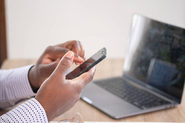 Les hommes d'affaires noirs africains sont assis sur des téléphones mobiles communiquant avec les clients et faisant des rapports financiers et étudiant l'analyse annuelle des bénéfices. Un comptable vérifie la situation financière de l'entreprise. - Photo, image