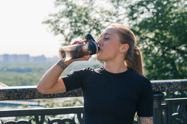 フィットネス若いスポーツウーマン少女は,公園の健康で街の屋外で運動しながら,朝の飲み水でスポーツをする - 写真・画像