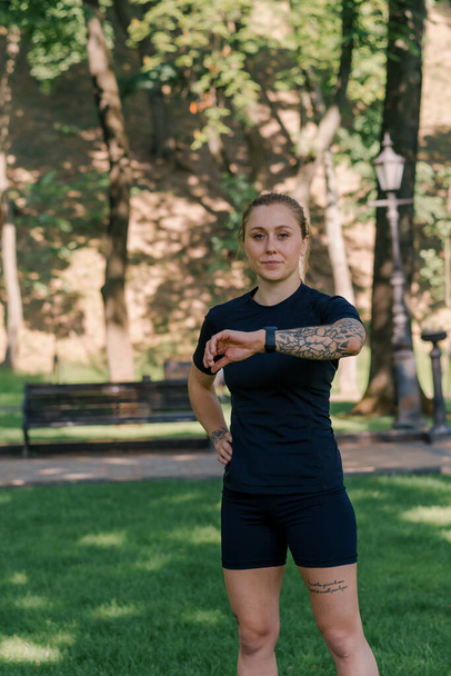 Portrét mladé sportovkyně, která kontroluje čas a puls na chytrých hodinkách po tréninku v konceptu zdravého životního stylu parku - Fotografie, Obrázek
