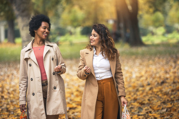 Mujer feliz amigos caminando en el bosque en otoño con bolsas de compras. - Foto, imagen