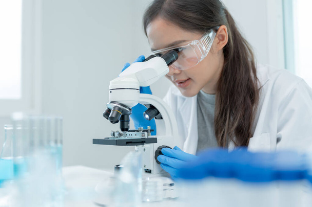 A tudós biokémiai mintákat analizál fejlett tudományos laboratóriumban. Orvosi professzionális használat mikroszkóp néz mikrobiológiai fejlődési vírus. Biotechnológiai kutatás a tudományos laborban. - Fotó, kép