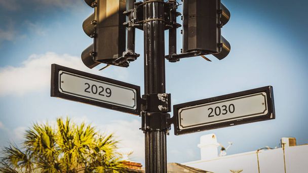 An image with a signpost pointing in two different directions in German. One direction points to 2029 the other points to 2030 - Photo, Image