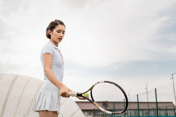 спортсменка проводит теннисную ракетку на корте, активную одежду, спортивную и спортивную, мотивацию, здоровье - Фото, изображение