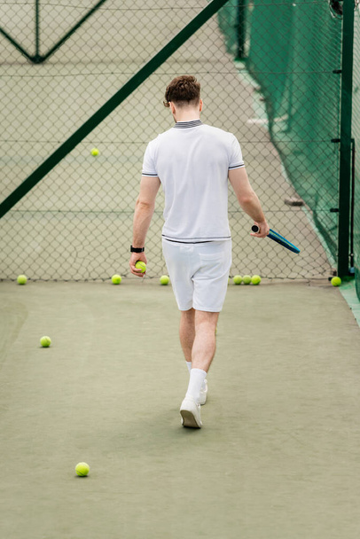 Tenis raketli erkek oyuncu sahada topların etrafında yürüyor, hobi ve motivasyon, arka plan - Fotoğraf, Görsel