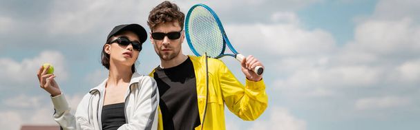 pancarta, pasatiempo y deporte, hombre y mujer con estilo en gafas de sol con raqueta y pelota en la cancha de tenis - Foto, Imagen