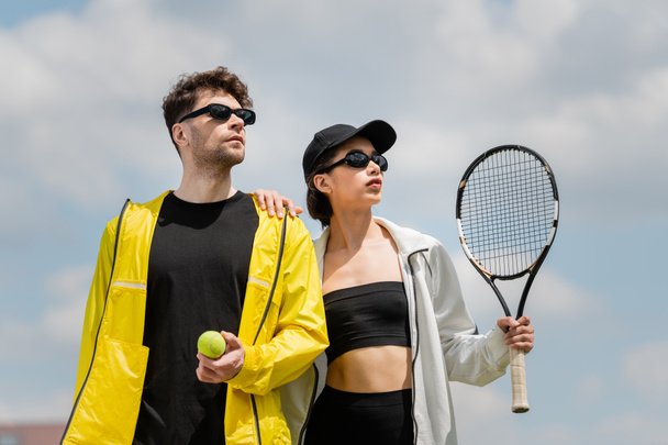 теннисный спорт и мода, мужчина и женщина в солнцезащитных очках, ракетка и мяч на теннисном корте, хобби - Фото, изображение