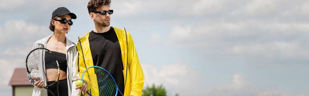 pancarta, deporte de verano, pareja en gafas de sol de pie en la cancha de tenis con raquetas, los atletas de moda - Foto, Imagen
