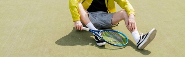 Banner, abgeschnittene Ansicht eines männlichen Tennisspielers, der auf dem Platz sitzt und Schläger in der Hand hält, Mann in aktiver Kleidung - Foto, Bild
