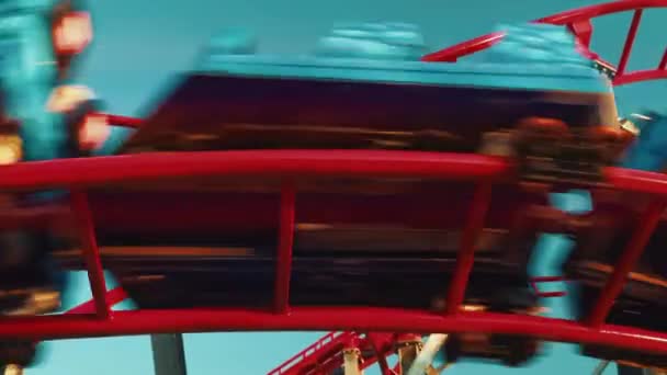 Close up bottom up view of twisting red roller coaster with sun reflections. Funfair and amusement park - Footage, Video