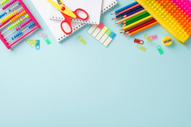 Delightful educational essentials arranged in a top view composition: a vivid assortment of colorful materials on a serene pastel blue background, providing copyspace for text or advertising - Photo, Image