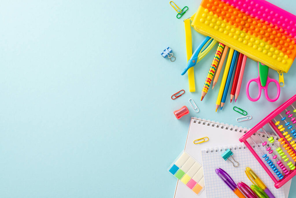 Dive into the joy of learning with this creative top-down snapshot: an array of colorful school supplies beautifully displayed on a pastel blue surface, offering copyspace for text or adverts - Photo, Image