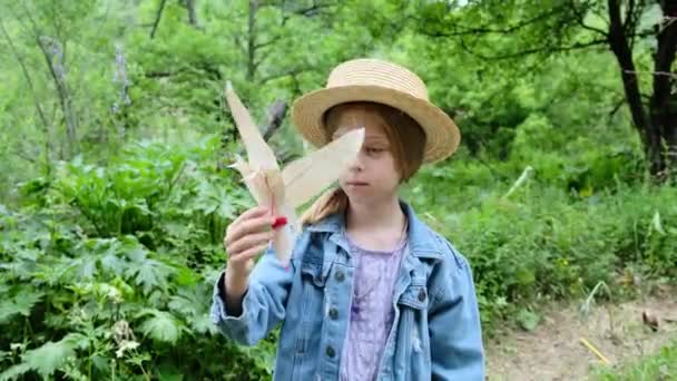 Dziewczyna w kapeluszu wypuszcza papierowego ptaka w powietrze w naturze. Wysokiej jakości materiał 4k - Materiał filmowy, wideo