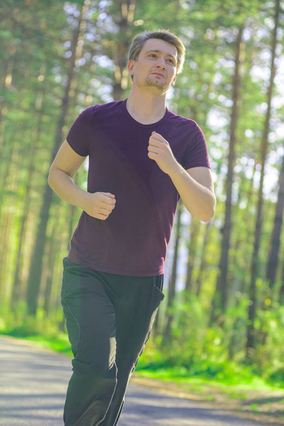 Running man jogging in city park at beautiful summer day. Sport fitness model caucasian ethnicity training outdoor. - Foto, immagini
